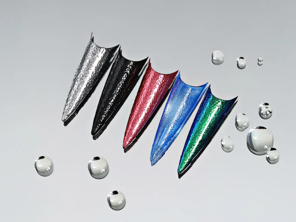 Five sharp stiletto nail swatches lined up showcasing different metallic chrome colors rubbed over 3D water ripple structures