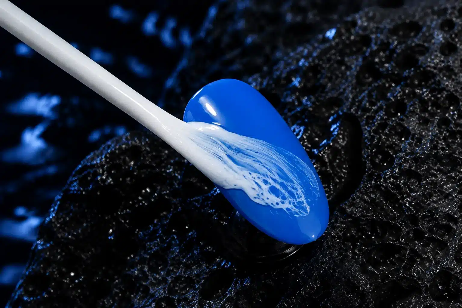 Round white brush applying JTING White Sea Wave Gel to a blue nail tip to create fluid wave and lace patterns
