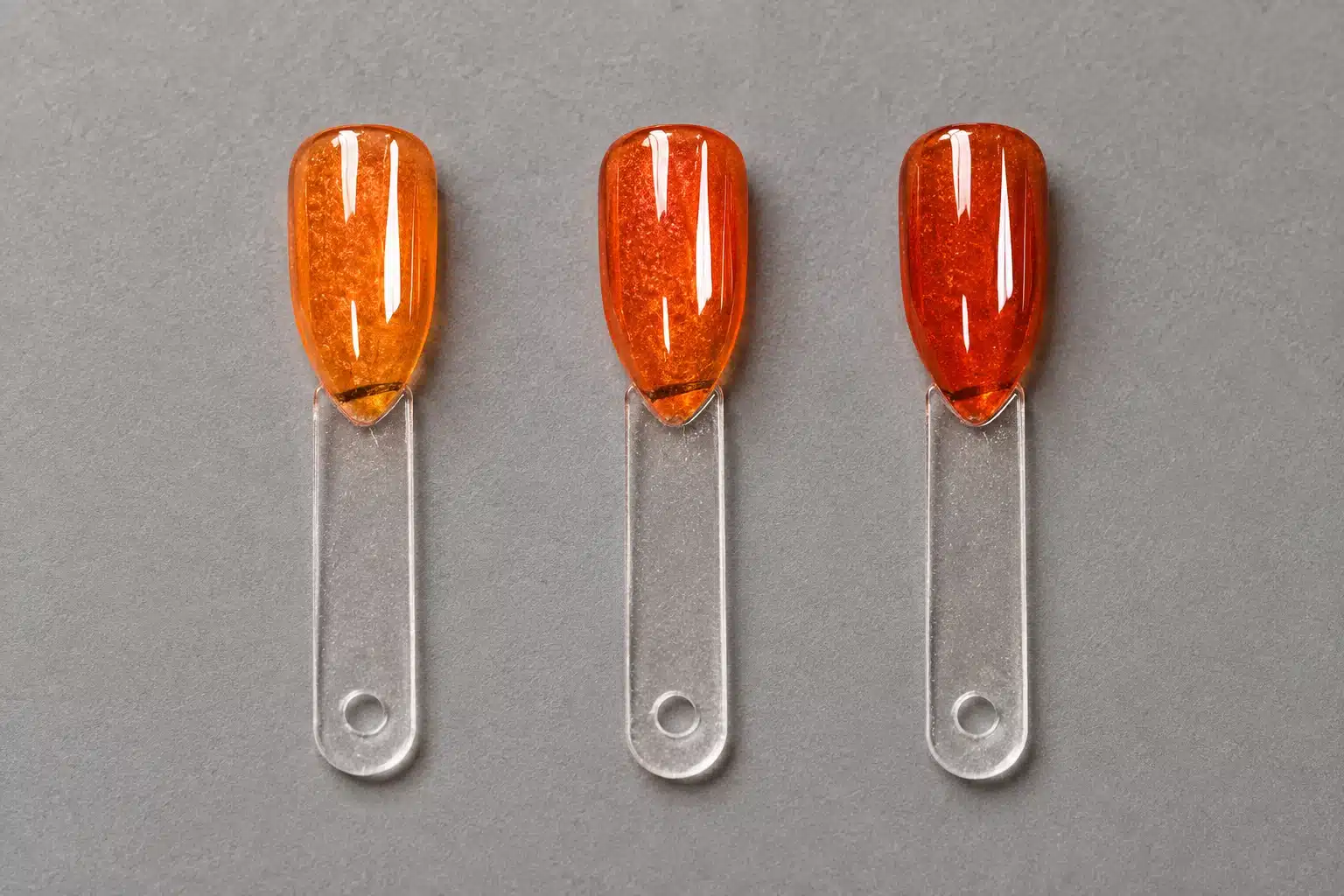 Three amber-orange jelly gel nail swatches arranged from lighter to deeper color.