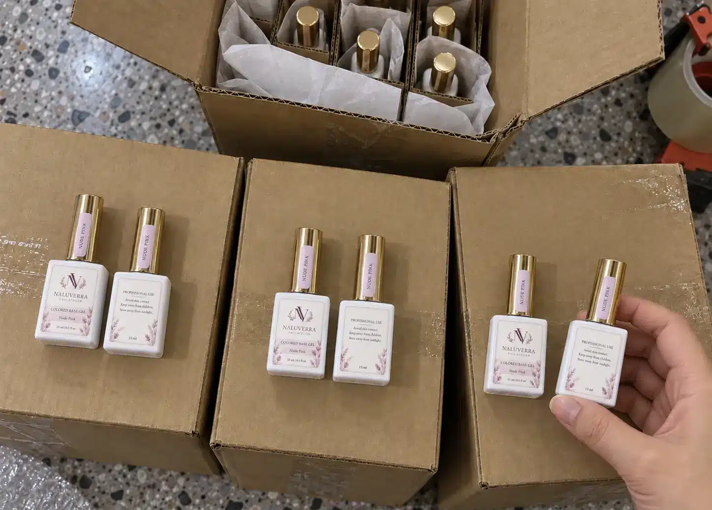 Labeled colored base gel bottles arranged on kraft cartons before packing