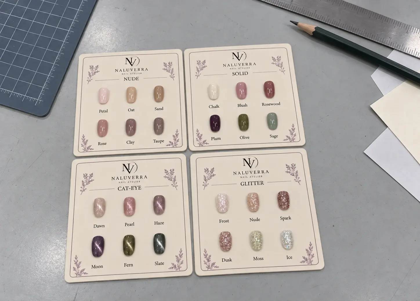 Four matte paper shade card prototypes with readable shade names on a packaging workbench