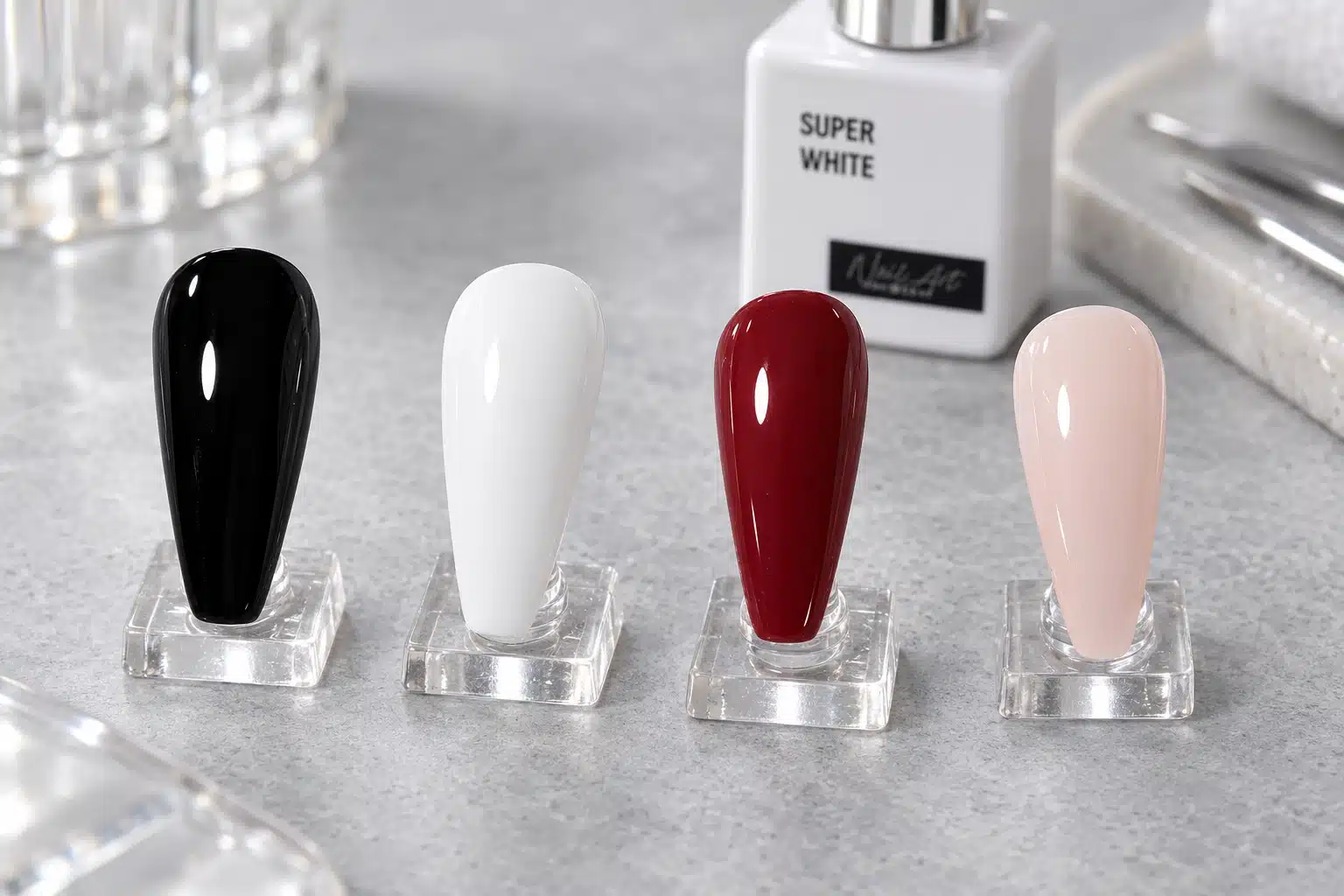 Black, white, burgundy and sheer nude-pink gel nail polish swatches on clear display stands