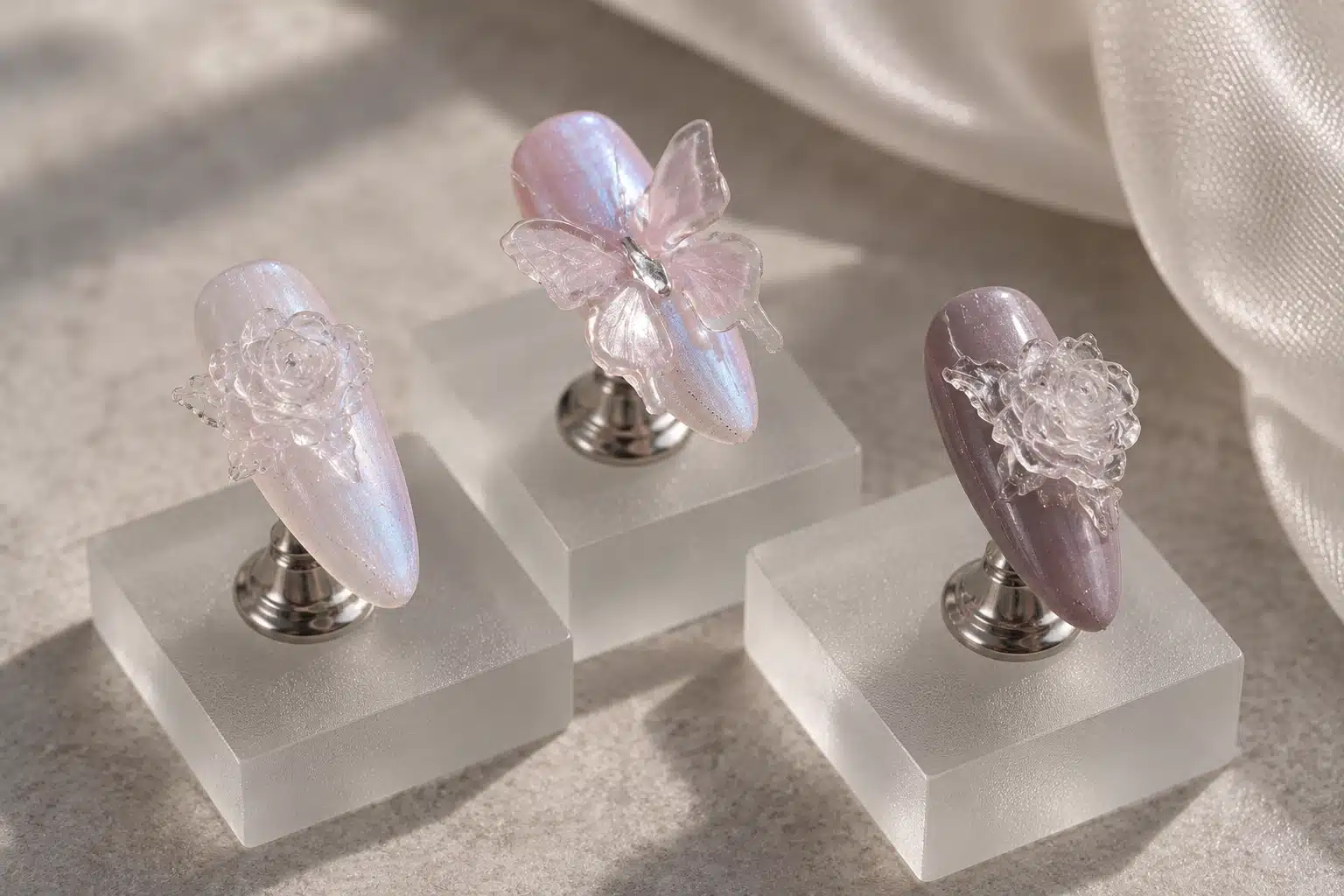 Base Colors beneath Clear Sculpted Nail Art Clear rose and butterfly nail designs on pearlescent pink and muted plum bases, mounted on separate stands
