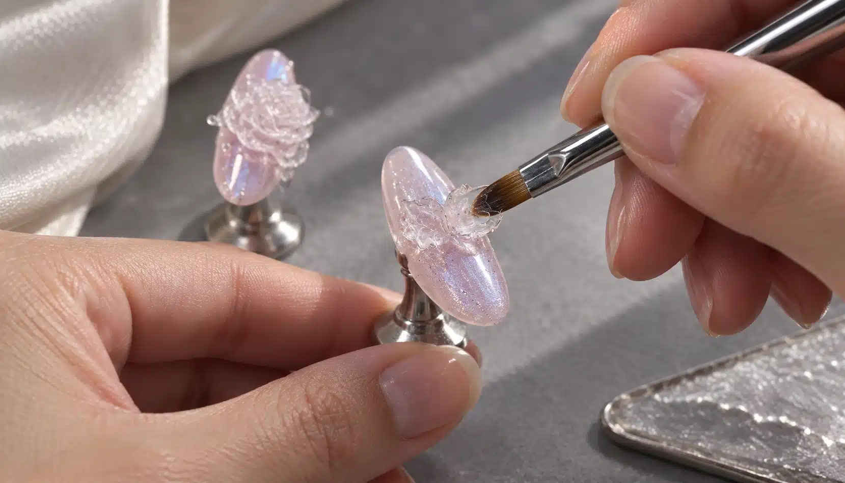 Shaping Thin Clear Gel Petals Technician pressing a thin clear gel petal with a sculpting brush on a mounted almond nail sample