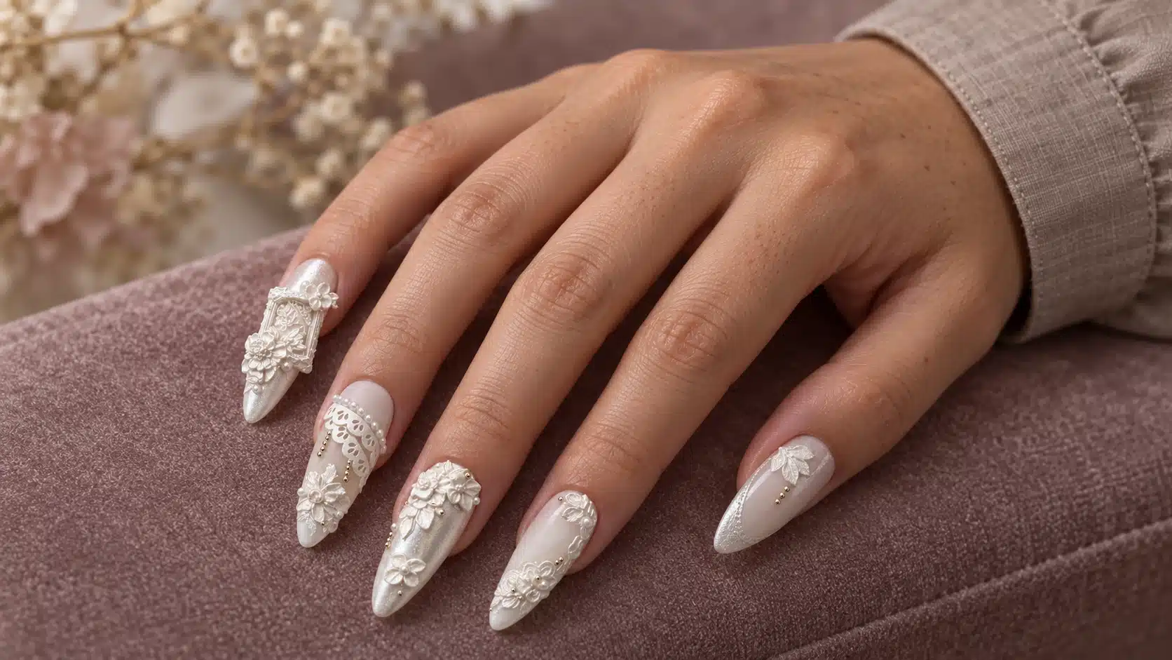 A hand model wearing dimensional white floral and lace-inspired sculpture gel nail art.