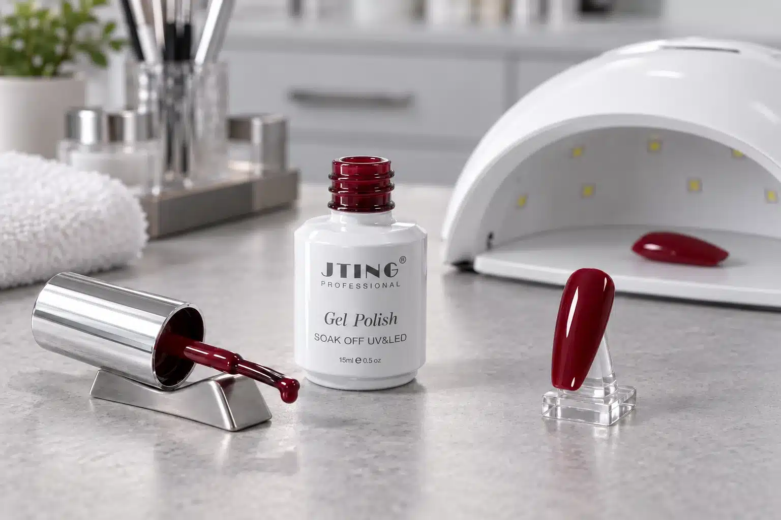 Burgundy gel nail polish, a loaded brush and a nail swatch beside a switched-off curing lamp