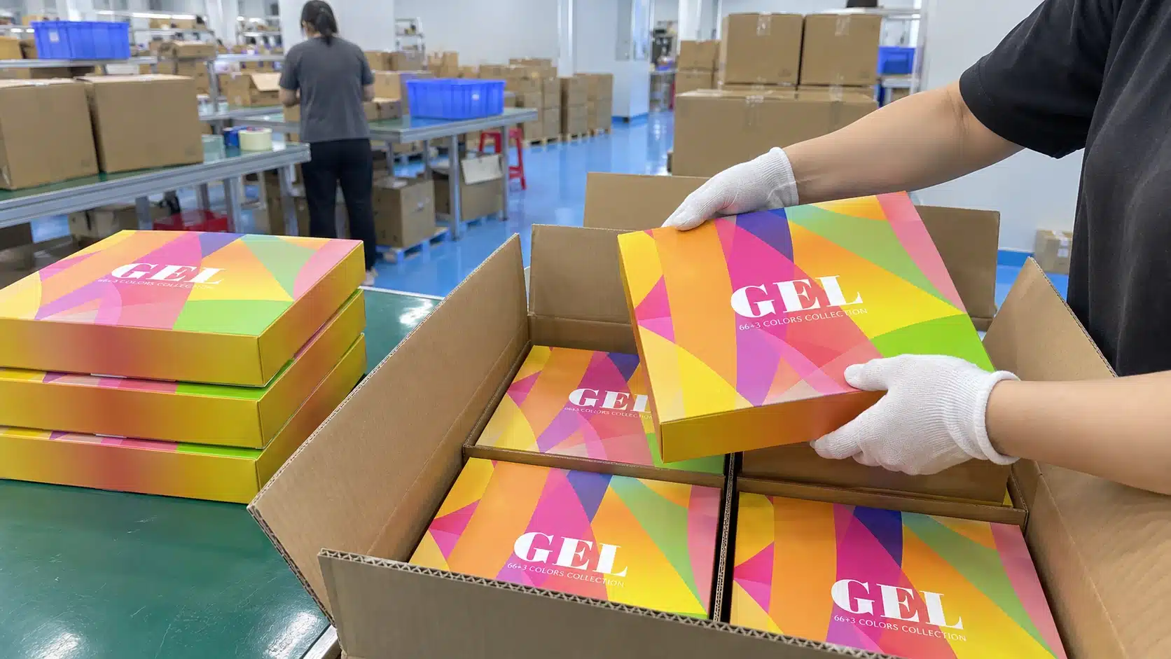 Worker packing gel nail polish collection boxes into a shipping carton