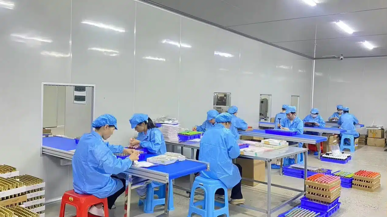 Workers in blue uniforms handling bottles and trays at JTING production workstations