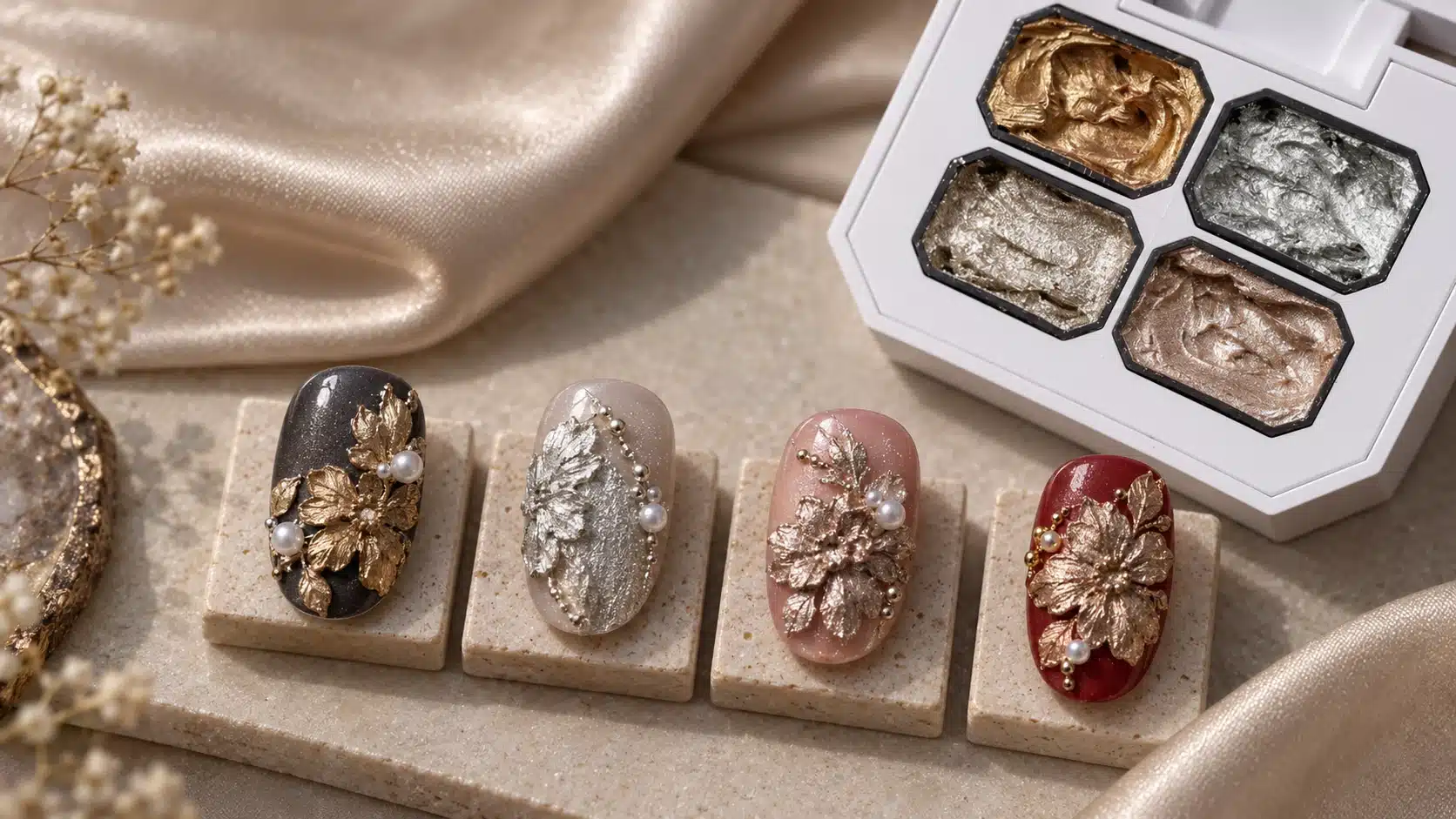 Four metallic floral nail designs on charcoal, nude, blush and red bases beside the four-well palette